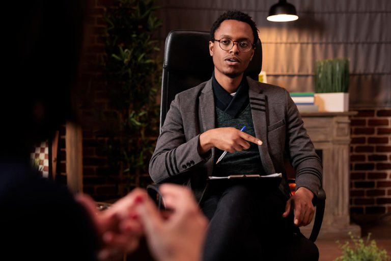 A professional man sitting in a chair offering debt counselling services.