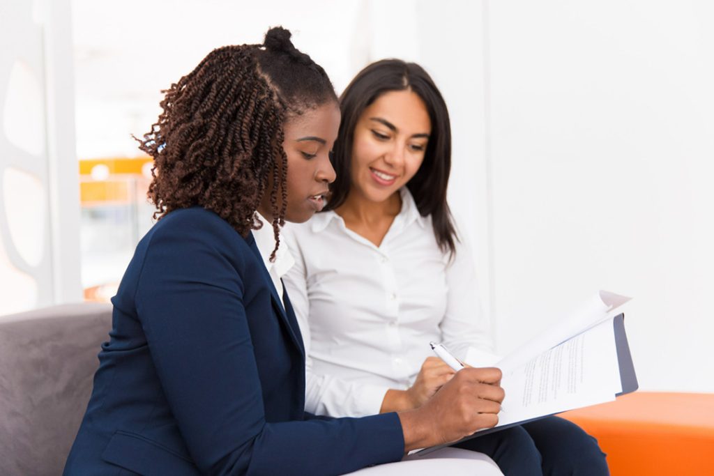 Two women sitting next to each other looking at a counselling sheet