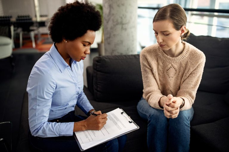 A young woman woman offering debt counselling services to another young woman sitting beside her.
